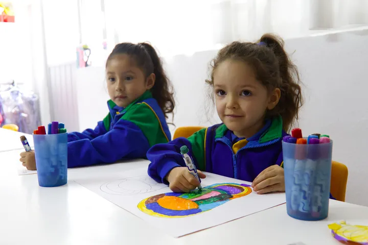 Niñas dibujando y coloreando en la mesa de actividades