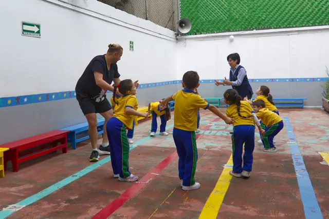 Niñas, niños y maestras jugando juntos en el patio de Happy Days