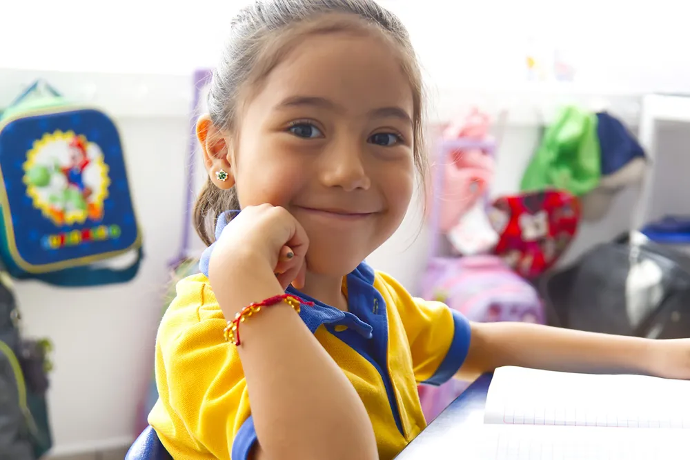 Niña de kínder sonriendo en su salón de Happy Days