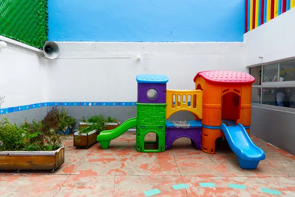 Área de juegos con resbaladilla y huerto en macetas